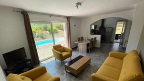 Ein modernes Wohnzimmer mit gelben Sofas, einem Fernseher und einem Essbereich mit Tisch und Stühlen.