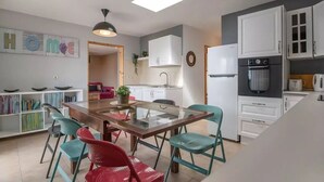 Una cocina moderna con armarios blancos, una mesa de comedor de vidrio y sillas color turquesa.