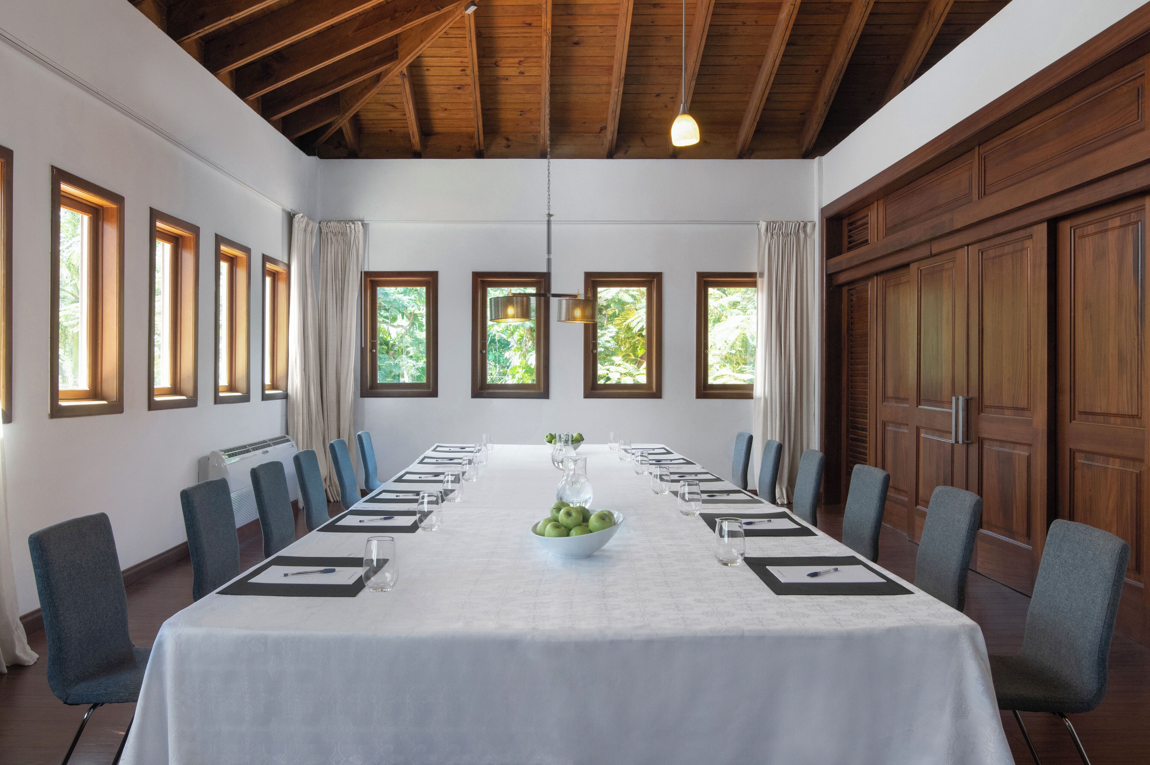 Une salle de conférence avec une longue table, des chaises et un plafond en bois.