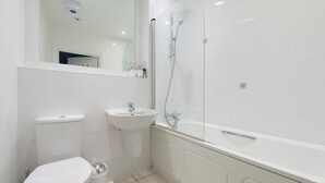 A modern bathroom with a toilet, sink, and bathtub. - Modern Luxury Appt by Bow Road Station (London)