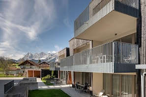 Un immeuble moderne à plusieurs étages, doté de balcons, d’un patio et offrant une vue sur les montagnes.