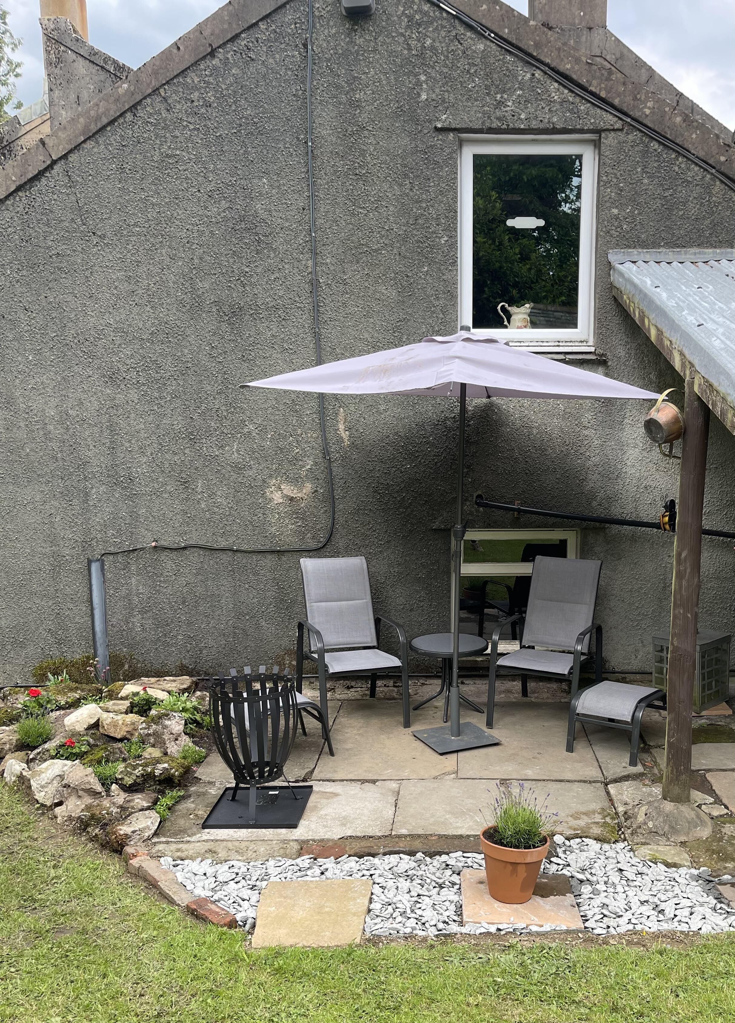 Un espace patio aménagé avec du mobilier d’extérieur, une table et une plante en pot.