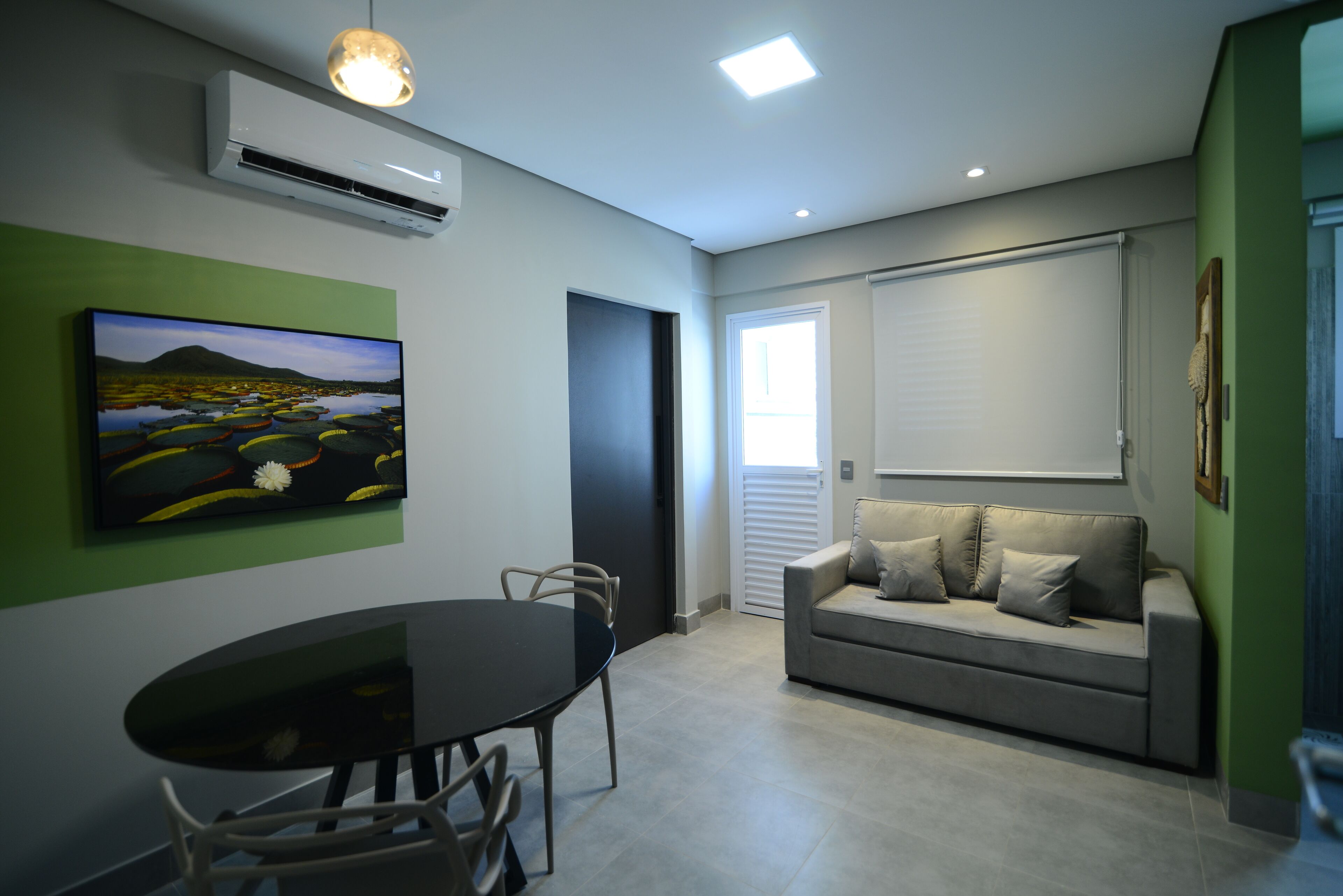 A modern living room with a dining table, a sofa, and a painting on the wall.
