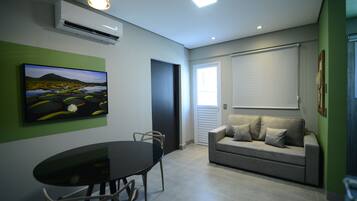 A modern living room with a dining table, a sofa, and a painting on the wall.