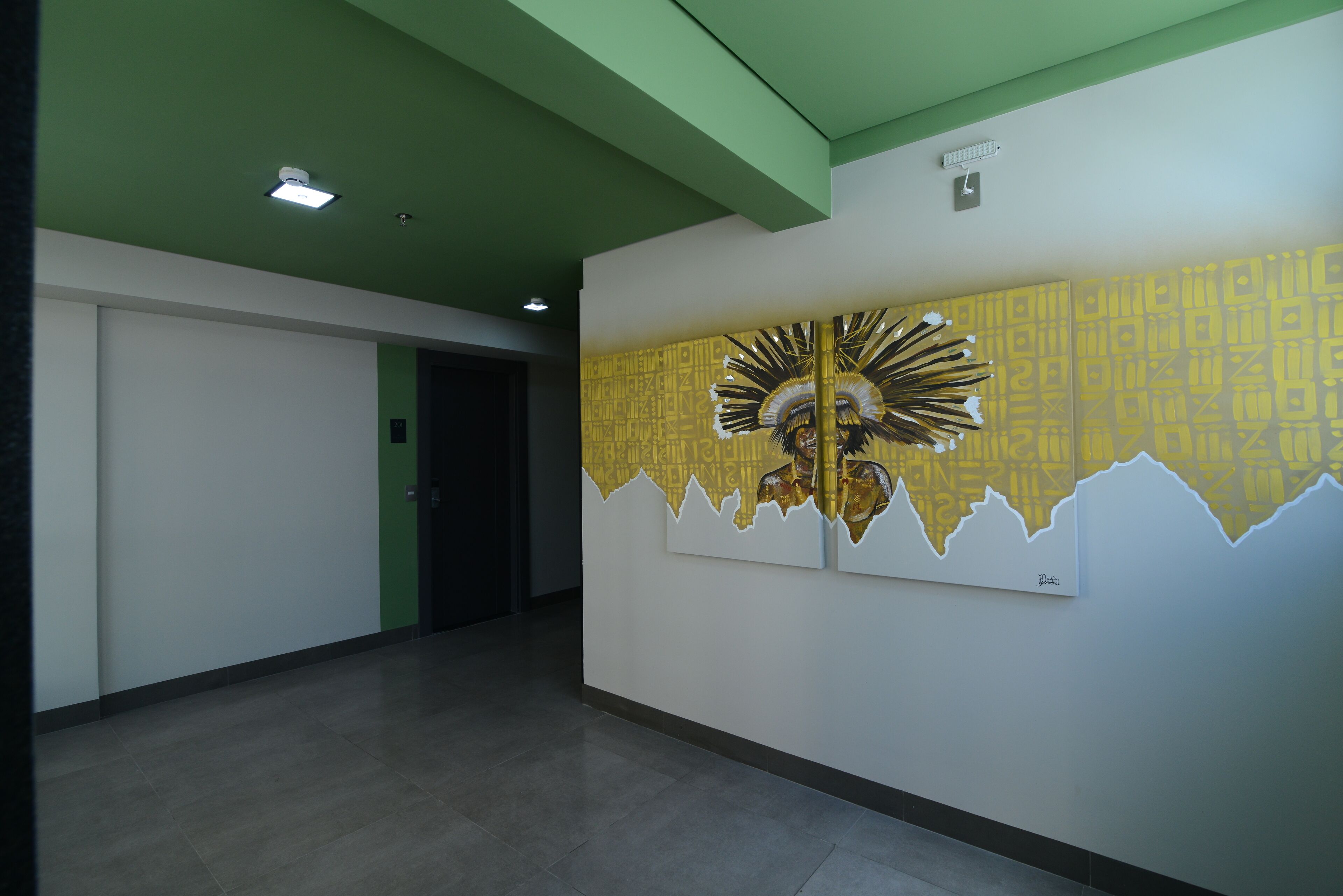 Um corredor com teto verde, porta branca e parede com um mural abstrato em amarelo e branco.