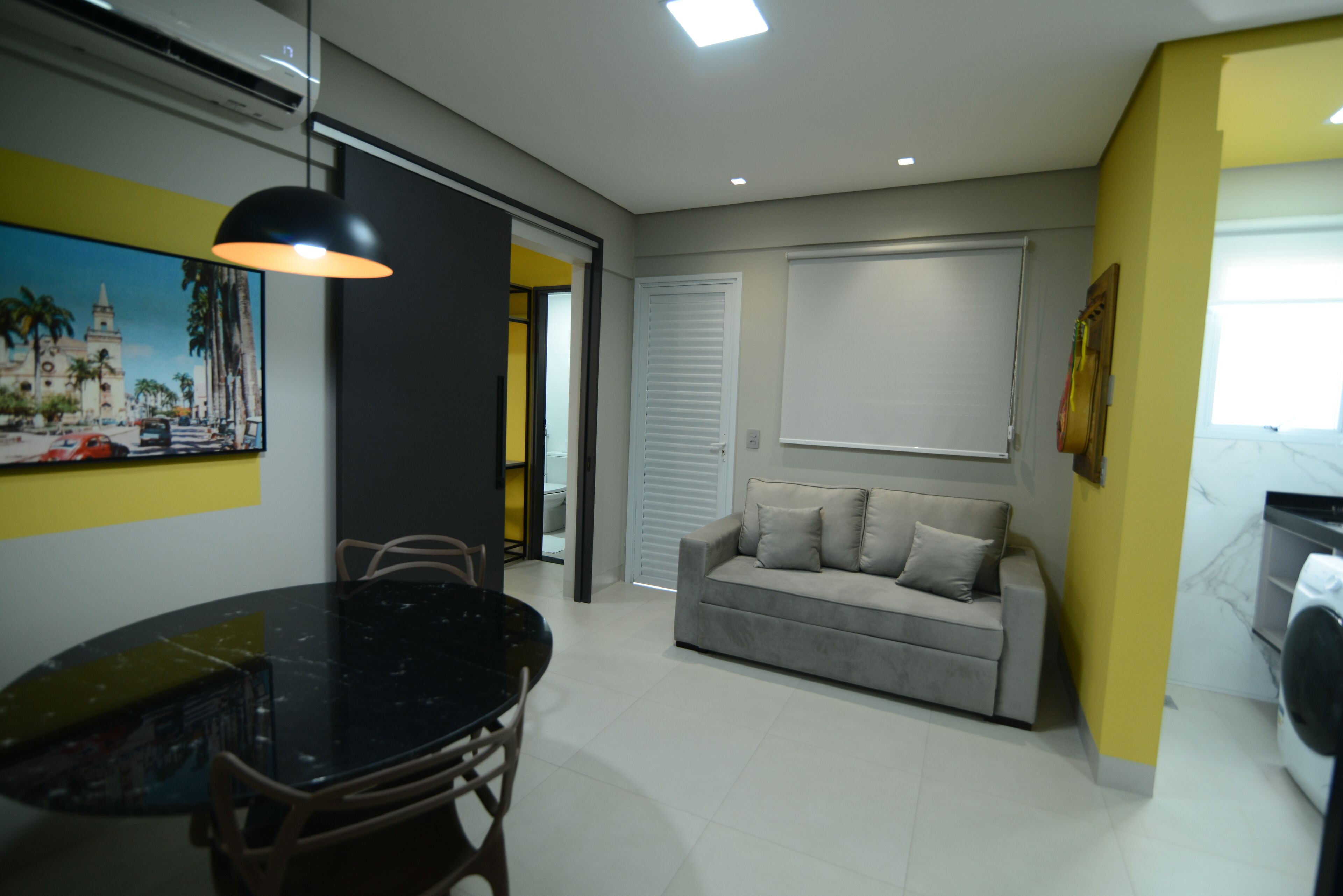 A modern living room with a dining area, a sofa, and a painting on the wall.