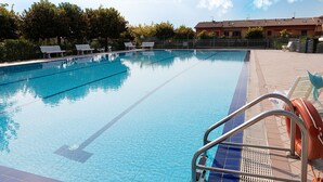 Ein klares Schwimmbecken mit Bahnen, einem Rettungsschwimmerstuhl und einer gefliesten Liegefläche.