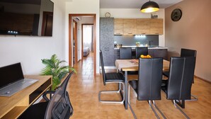Eine moderne Küche mit Holzausstattung, eine Essecke mit Tisch und Stühlen sowie eine Wanduhr.