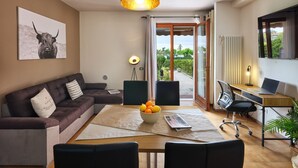 Ein modernes Wohnzimmer mit einer Couch, einem Esstisch und einem Laptop auf einem Schreibtisch.