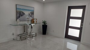 A modern interior with a glass console table, a potted plant, and a door with frosted glass panels. - CAPE CORAL FLORIDA DREAM $155  last minute  (Cape Coral)