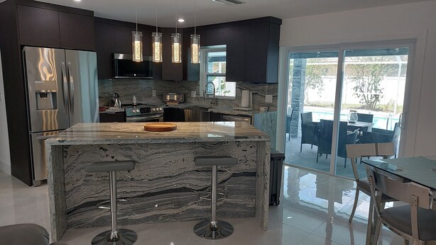 A modern kitchen with a marble island, stainless steel appliances, and pendant lighting. - CAPE CORAL FLORIDA DREAM $155  last minute  (Cape Coral)