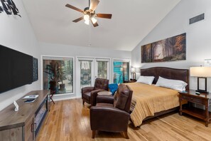 Une chambre d’hôtel équipée d’un lit, d’un bureau, d’une chaise, d’un ventilateur de plafond et d’une grande fenêtre.