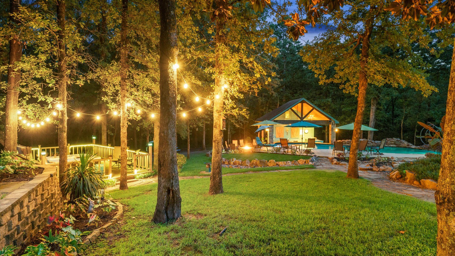 Ein Haus mit Pool, umgeben von Bäumen und einer Terrasse mit Lichterketten.