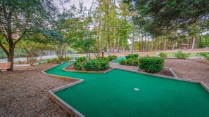 A miniature golf course with multiple holes, surrounded by trees and shrubs.