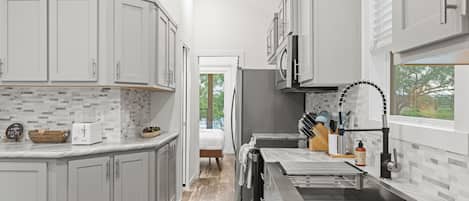 A modern kitchen with white cabinets, a marble countertop, and a built-in oven.