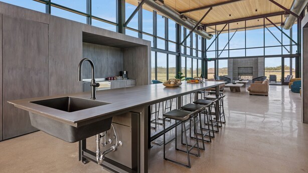 A modern kitchen with a large island, bar stools, and a view of the desert. - SKYE Texas Hill Country Resort  (Fredericksburg)
