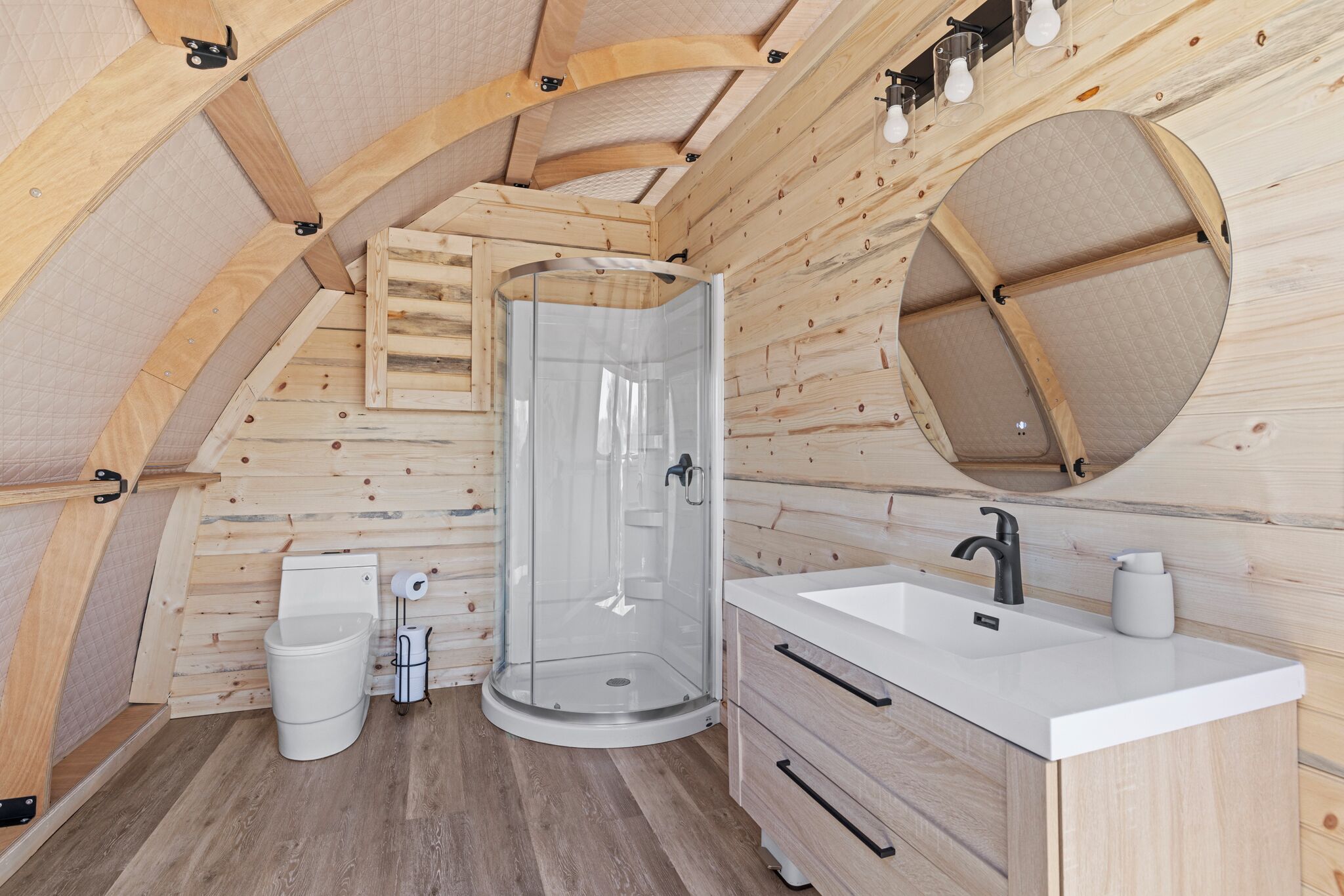 Ein kleines Badezimmer in einer Holzhütte, mit Dusche, Toilette und Waschbecken.
