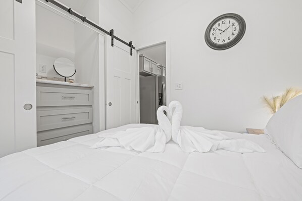 Un dormitorio con cama, cómoda, espejo, reloj y armario.