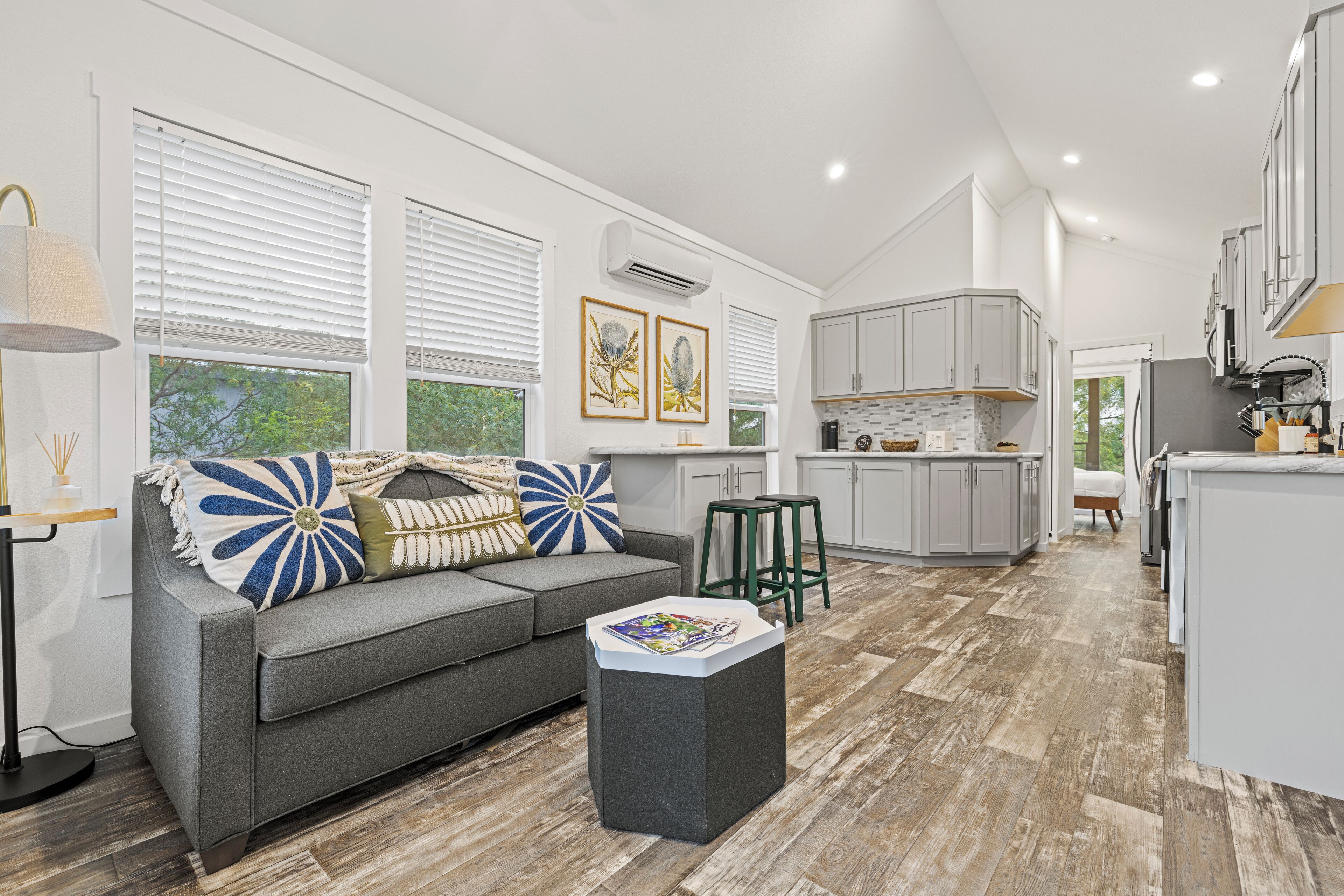 A modern living room with a grey sofa, a coffee table, and a view of the kitchen.