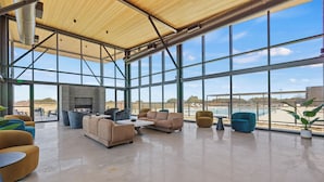 A spacious indoor area with large windows, a fireplace, and various seating arrangements. - SKYE Texas Hill Country Resort  (Fredericksburg)
