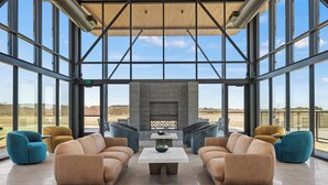 A spacious indoor area with large windows, a fireplace, and modern furniture. - SKYE Texas Hill Country Resort  (Fredericksburg)