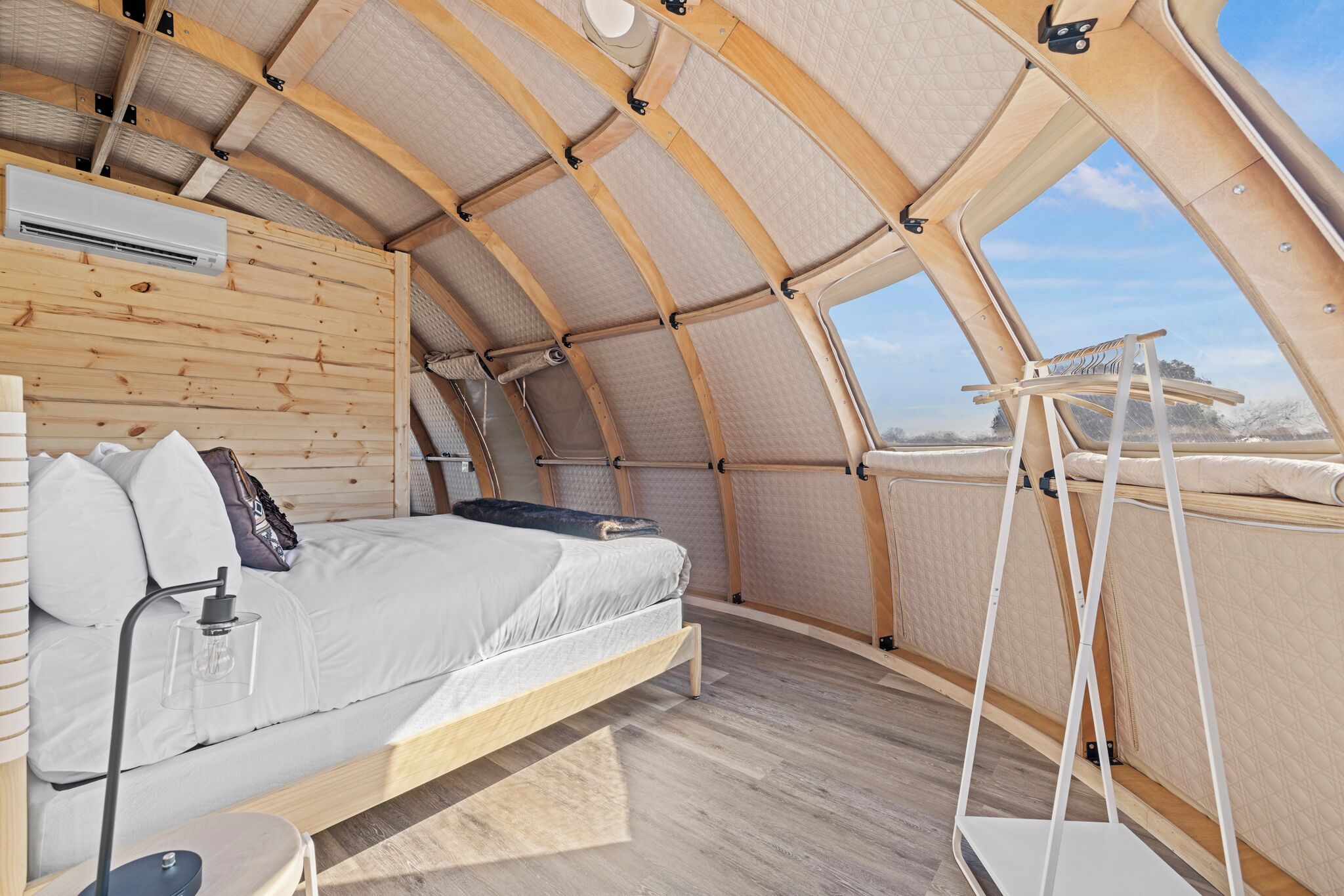 Una habitación acogedora, con techo curvo, una cama, una mesita y una escalera.