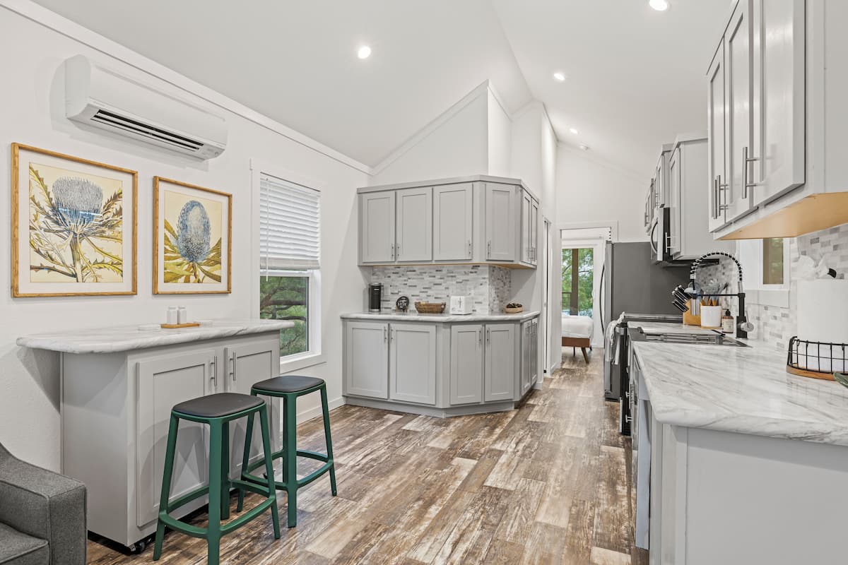 A modern kitchen with white cabinetry, a marble countertop, and a central island.