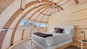 A cozy, circular room with a bed, a small table, and a window. - SKYE Texas Hill Country Resort  (Fredericksburg)