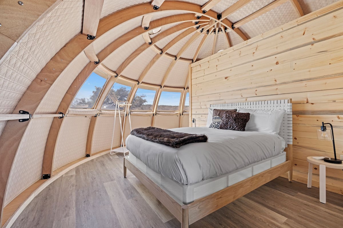 A cozy, circular room with a bed, a small table, and a window.