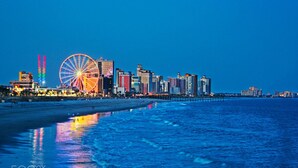 A coastal cityscape at dusk with a prominent Ferris wheel and illuminated buildings. - CMI Hotel 1935 Myrtle Beach SC (Myrtle Beach)