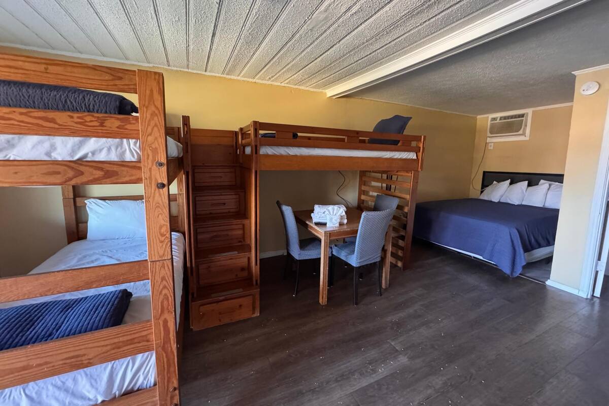 Una habitación con literas, un escritorio, una silla y una cama.