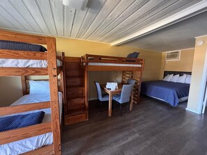 A room with bunk beds, a desk, a chair, and a bed.