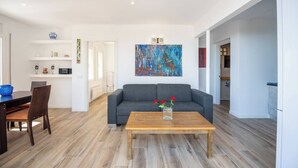 Una sala moderna con un sofá gris, una mesa de centro de madera y un cuadro en la pared.