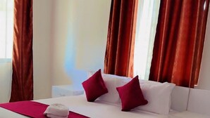 A hotel room with a bed, a nightstand, a ceiling fan, and curtains.