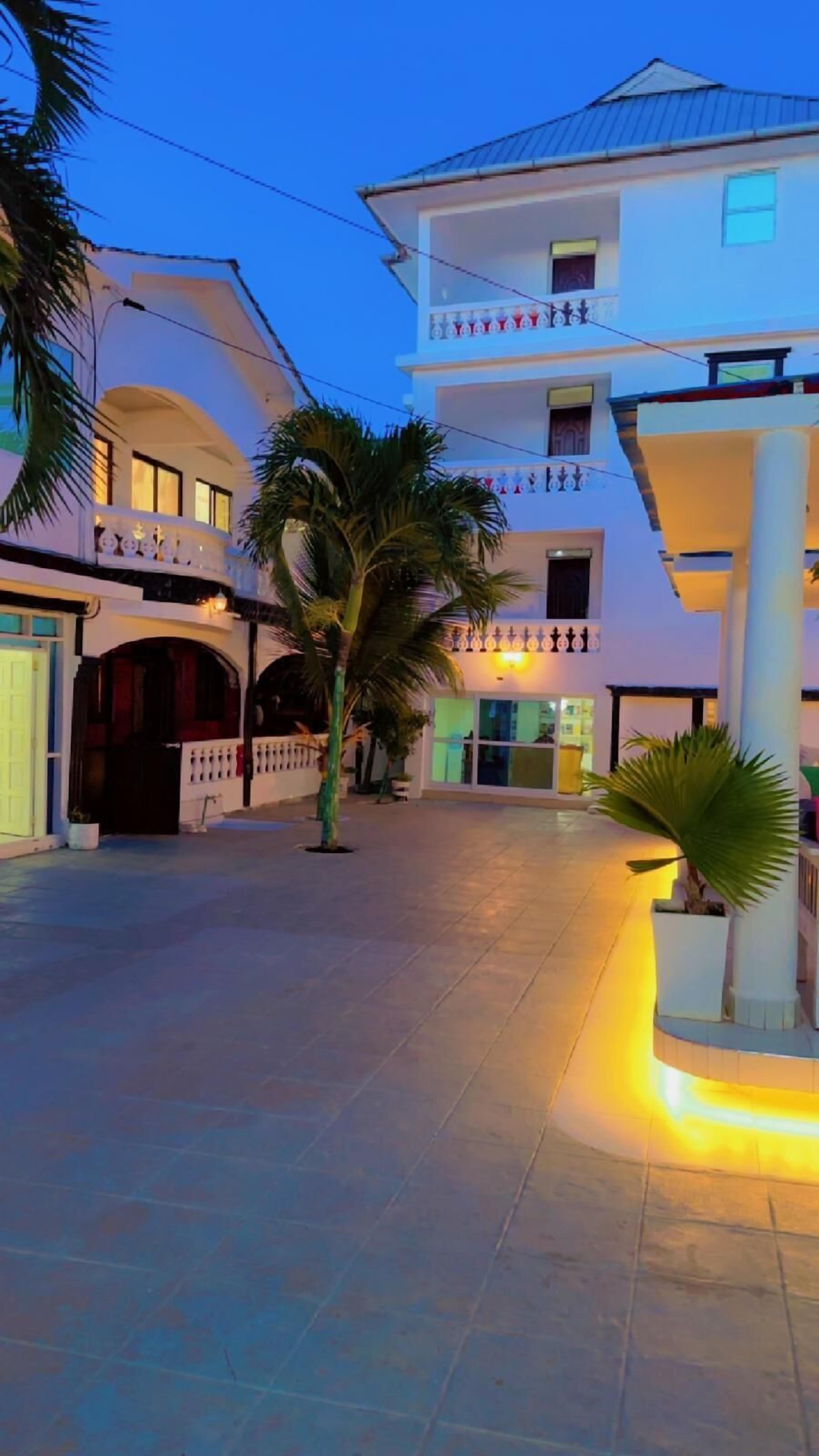 A multi-story building with a balcony, a gated entrance, and a well-lit pathway.