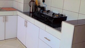 A kitchen with white cabinets, a gas stove, and a coffee maker.