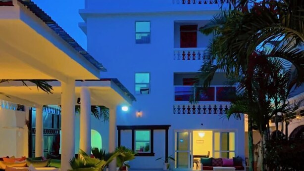 A multi-story hotel with a tiled courtyard, outdoor seating, and potted plants.