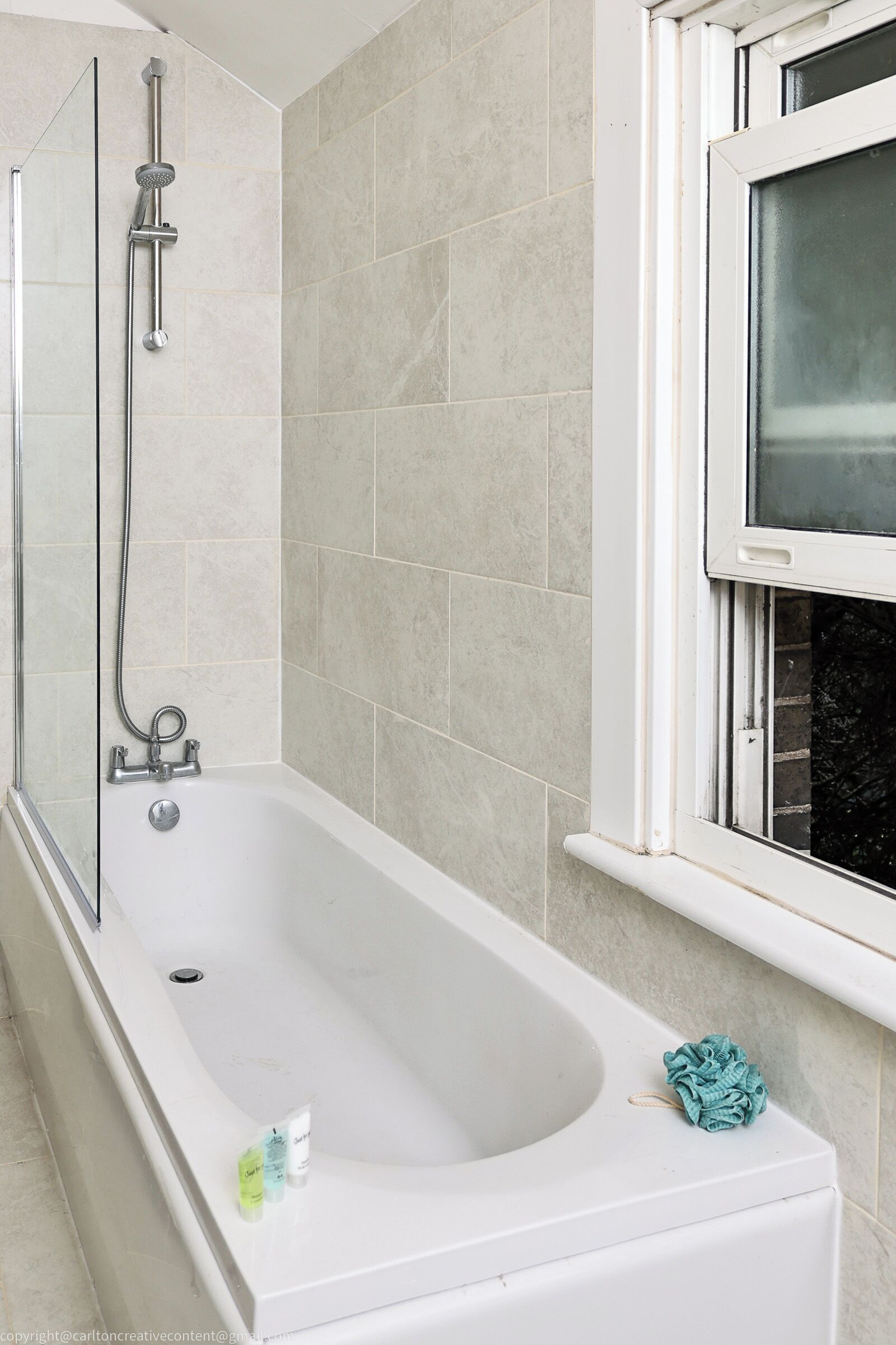 A bathroom with a bathtub, a shower, and a window.
