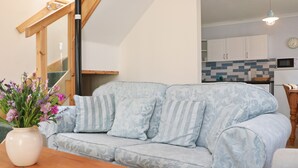 Un salon avec un canapé bleu clair, une table basse en bois et un vase de fleurs.