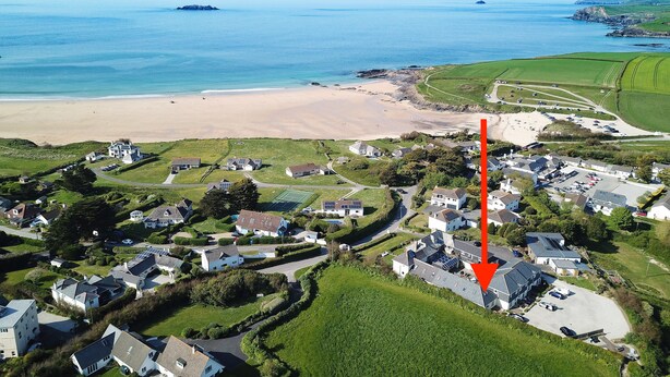Vue aérienne d’une zone résidentielle côtière, avec des maisons, une plage et une vaste étendue d’eau.