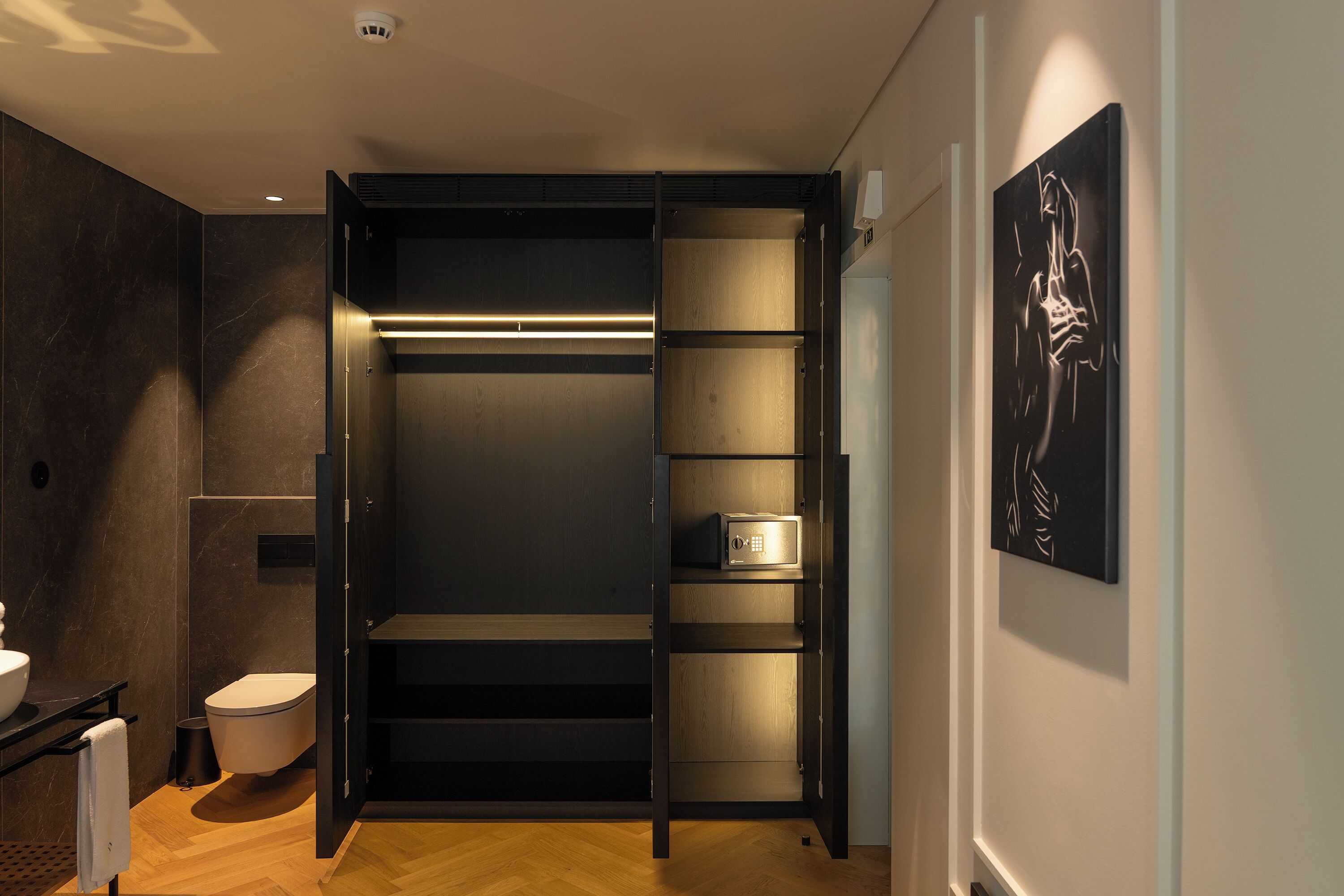 A modern bathroom with a toilet, sink, and open shelving unit.