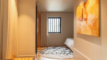 Une chambre à coucher avec un lit, une fenêtre, un tableau et un tapis à motifs.