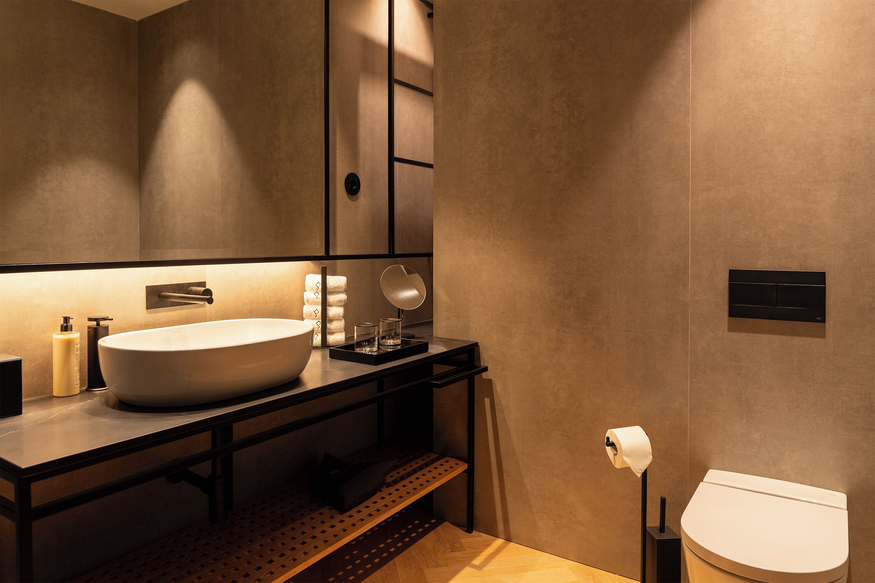 Un baño moderno con un lavamanos grande, un espejo y un inodoro.