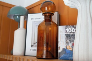 Une étagère avec une bouteille marron, un vase blanc et un livre intitulé « 100 intérieurs du monde entier ».