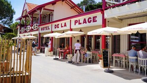 Un hôtel appelé «Hôtel de la Plage», doté d’une terrasse et de parasols.