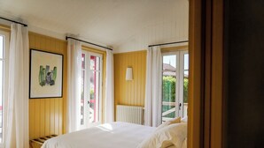 Une chambre à coucher avec un lit, une fenêtre avec des rideaux, un radiateur et un tableau encadré au mur.