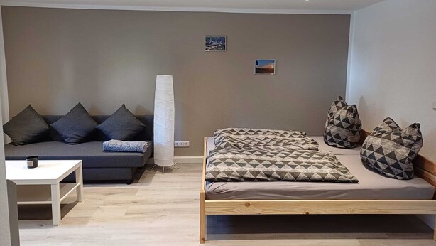 Ein gemütlicher Raum mit einem Bett, einer Schlafcouch und einem kleinen Tisch.
