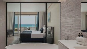 A modern hotel room with a large bed, a glass wall offering a sea view, a separate seating area, and a large bathtub. - Dom Pedro Residences  (Loulé)