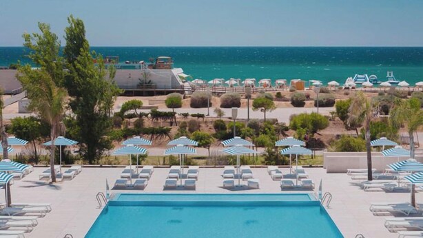 A pool area with lounge chairs and umbrellas, overlooking a beach and the sea. - Dom Pedro Residences  (Loulé)