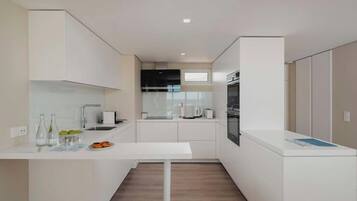 A modern kitchen with white cabinetry, a central island, and a built-in oven.